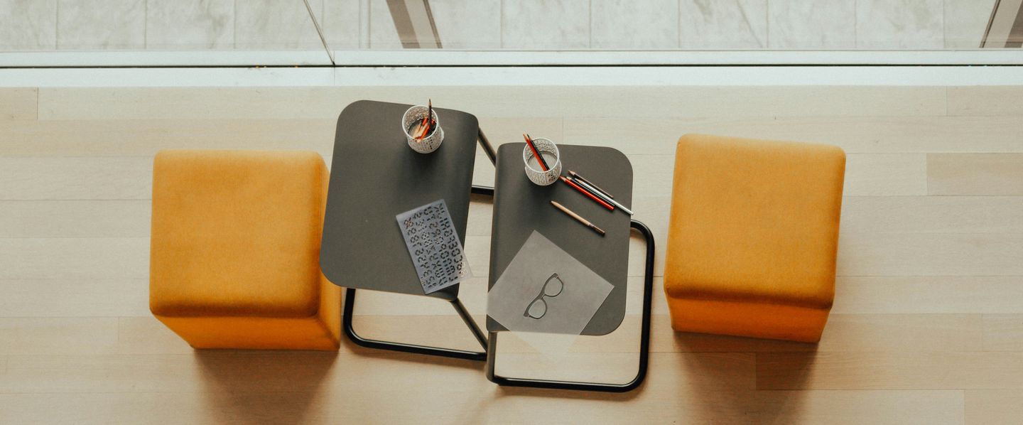Two orange stools facing a low table in a meeting corner