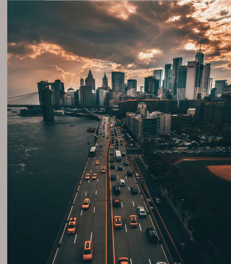 Aerial view of a city skyline at dusk with traffic crossing a bridge