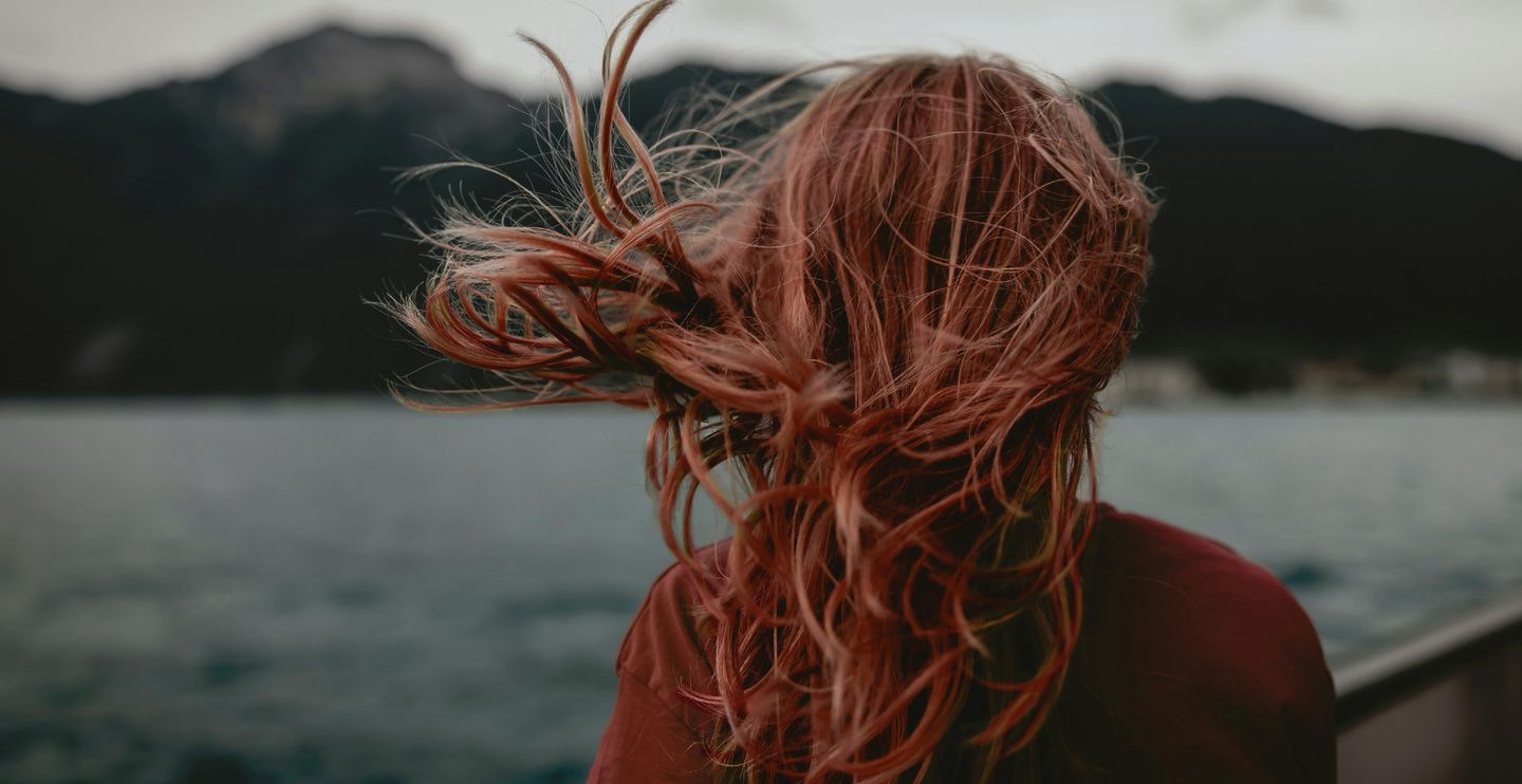 Woman on a lake shore, hair blowing in the wind