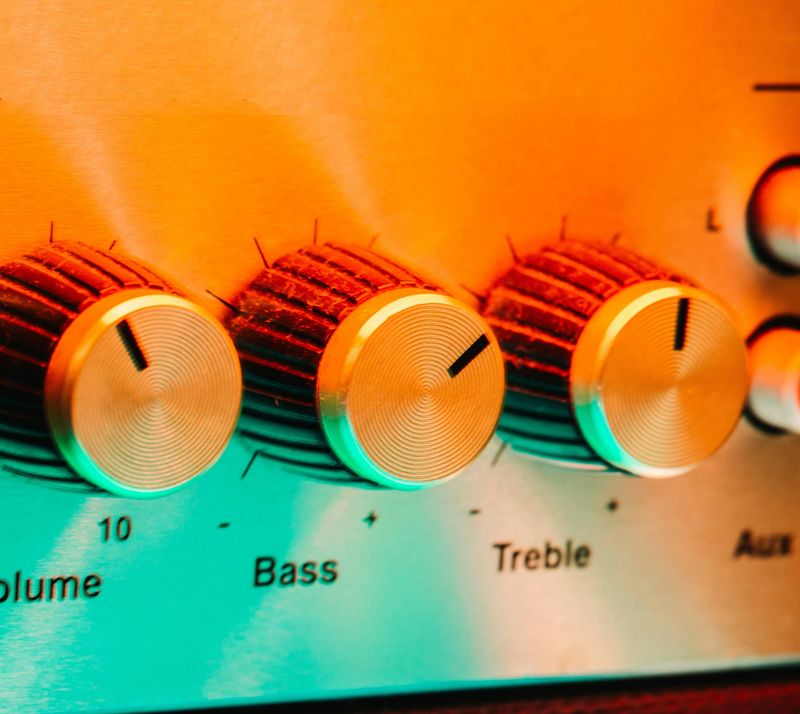 Close-up of amplifier knobs labelled volume, bass and treble